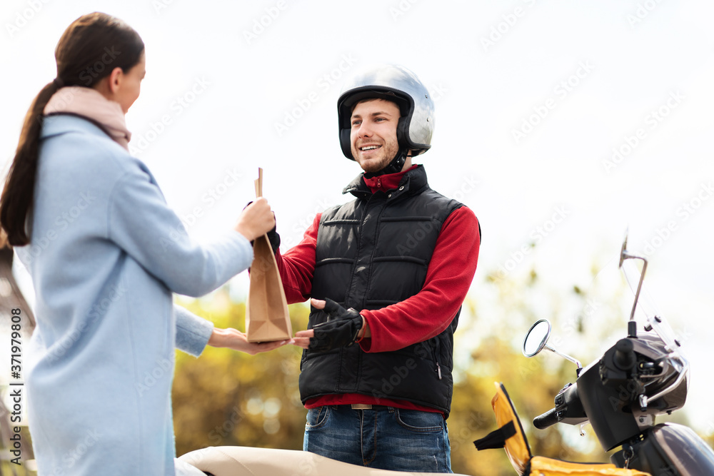 Delivery Man Giving Package To Customer Standing With Scooter Outside