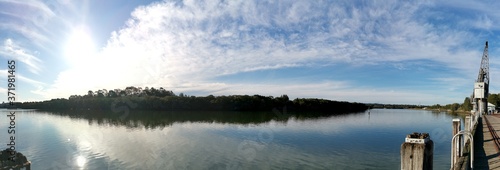 Beautiful afternoon view of a river with reflections of sun, blue sky, white puffy clouds and trees on water, Parramatta River, Blaxland Riverside Park, Sydney, New South Wales ,Australia
