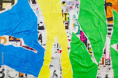 Torn and crumpled blue, green and yellow glossy paper on abstract colorful collage of magazine paper pieces and clippings with letters and numbers background.