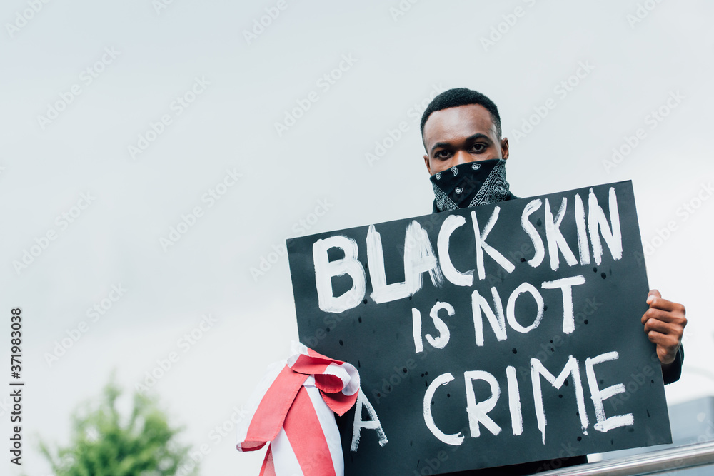 african american man holding placard with black skin is not a crime lettering while looking at camera african american man holding placard with black skin is not a crime lettering while looking at camera
