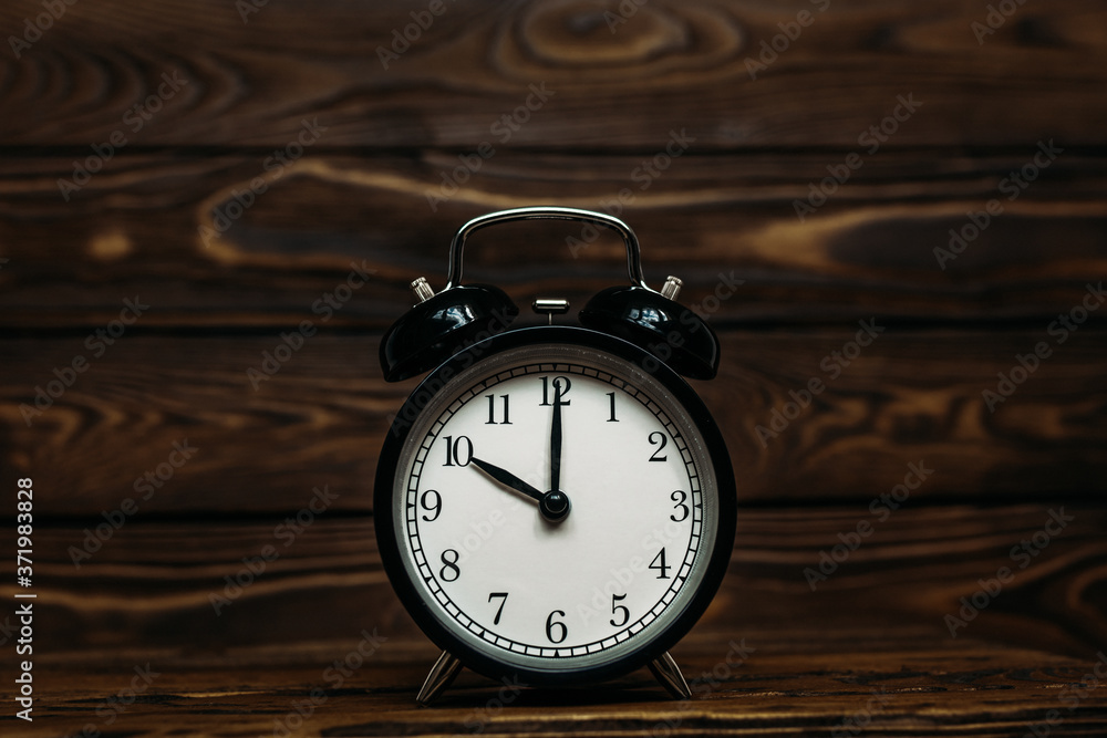 Clock on a wooden background. The clock shows the time of ten o'clock in the afternoon. Clock showing the time of ten o'clock in the morning. An image of a retro clock showing 10:00 pm/am. Copy space Clock on a wooden background. The clock shows the time of ten o'clock in the afternoon. Clock showing the time of ten o'clock in the morning. An image of a retro clock showing 10:00 pm/am. Copy space