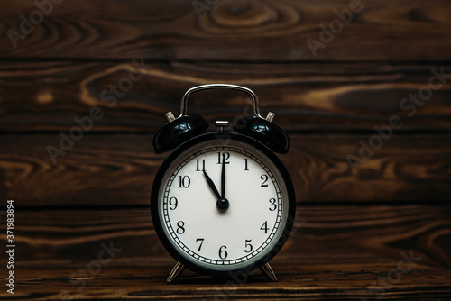 Clock on a wooden background. The clock shows the time of eleven o'clock in the afternoon. The clock shows the time of eleven o'clock in the morning. An image of a retro clock showing 11:00 pm/am. 