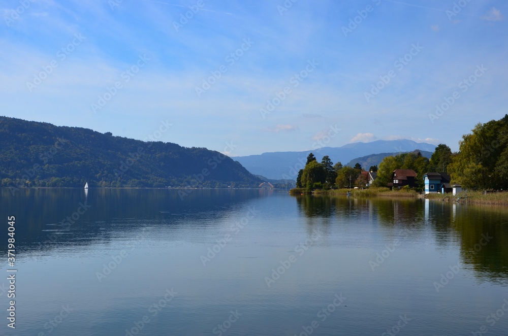 Ossiacher Lake in Kaernten (Carinthia) in autumn, Austria, view from village of Bodensdorf, mountains on horizon, blue sky background