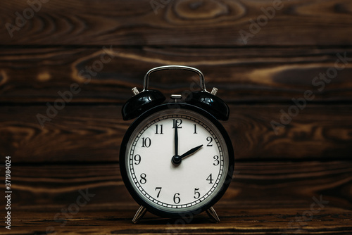 Clock on a wooden background. The clock shows the time of two o'clock in the afternoon. Clock showing the time of two o'clock in the morning. An image of a retro clock showing 02:00 pm/am. Copy space