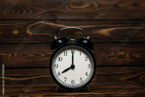 Clock on a wooden background. The clock shows the time of eight o'clock in the afternoon. The clock shows the time of eight o'clock in the morning. An image of a retro clock showing 08:00 pm/am. 