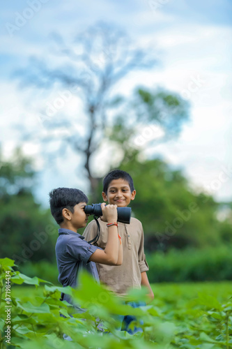 Tow little Indian boy enjoys in nature with binoculars © Niks Ads