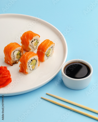 sushi rolls on a white plate on a blue background.