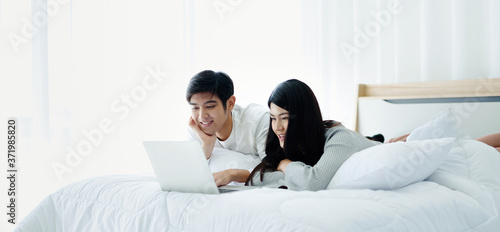 Couples lie prone on the bed Video call via notebook Modern Technology in bed