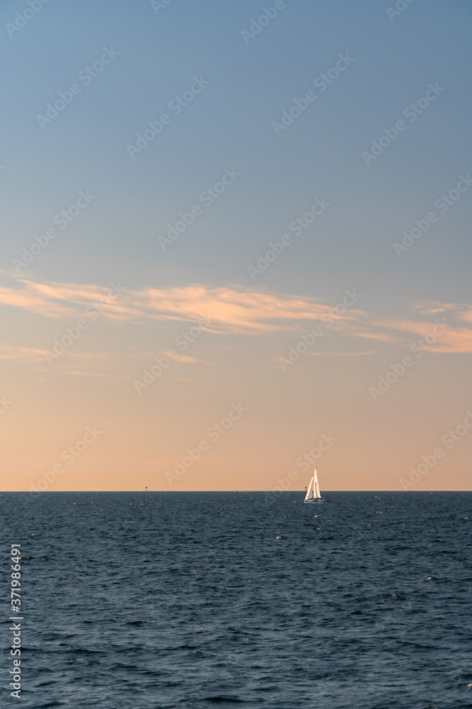 White sailboat on a calm sea or ocean during sunset. Large copy space. Minimalistic style.