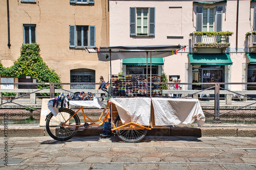 Mobile sunglasses stand tricycle on the side of Navigli Grand canal
