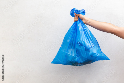 hand holding a blue plastic garbage bag
