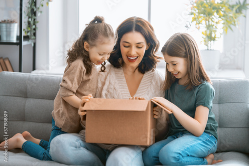 Mother and daughters are unpacking cardboard photo