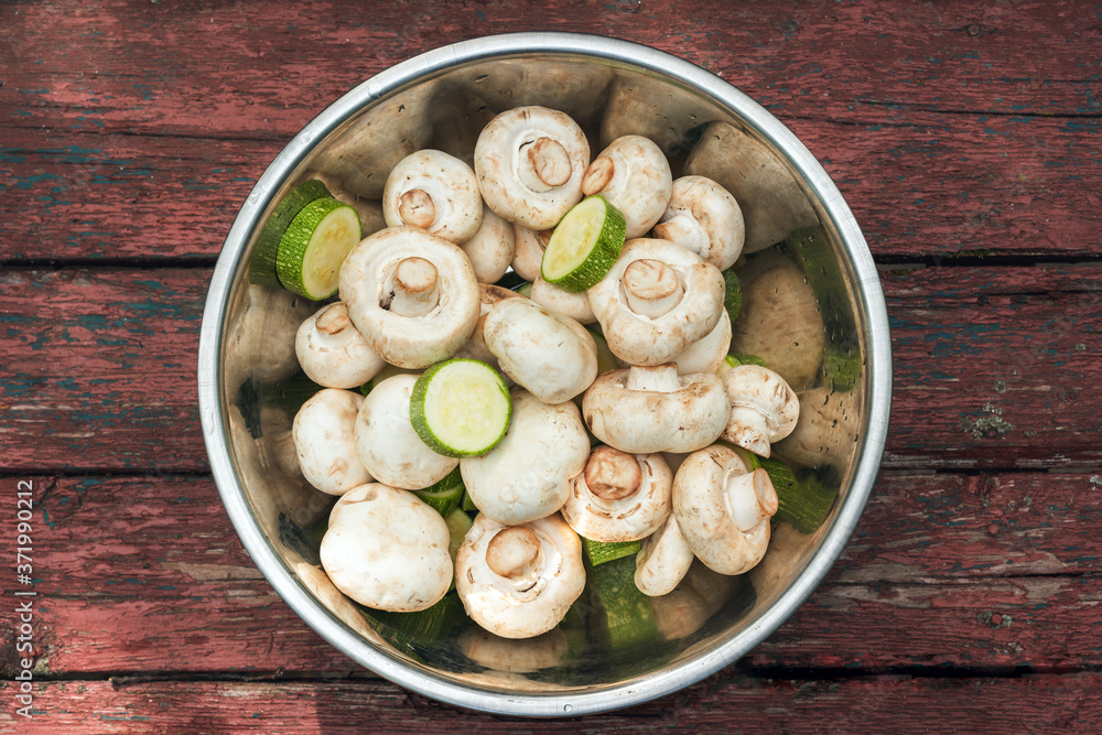 Raw mushrooms champignons in a bowl on a wooden table Raw mushrooms champignons in a bowl on a wooden table