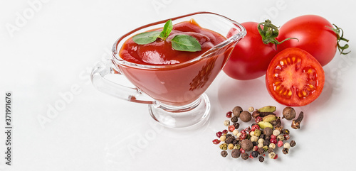 Cherry tomatoes, spices and a glass sauceboat with ketchup on a white background. Seasonings, tomato sauce and tomato
