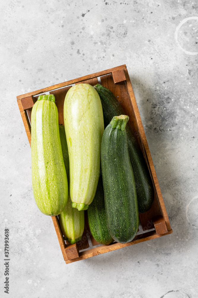 Raw zucchini. Zucchini in a wooden box on a light gray table. Top view with space for text. Zucchini crop