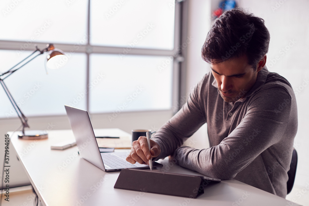 Fototapeta premium Businessman Working From Home Drawing On Digital Tablet Using Stylus Pen