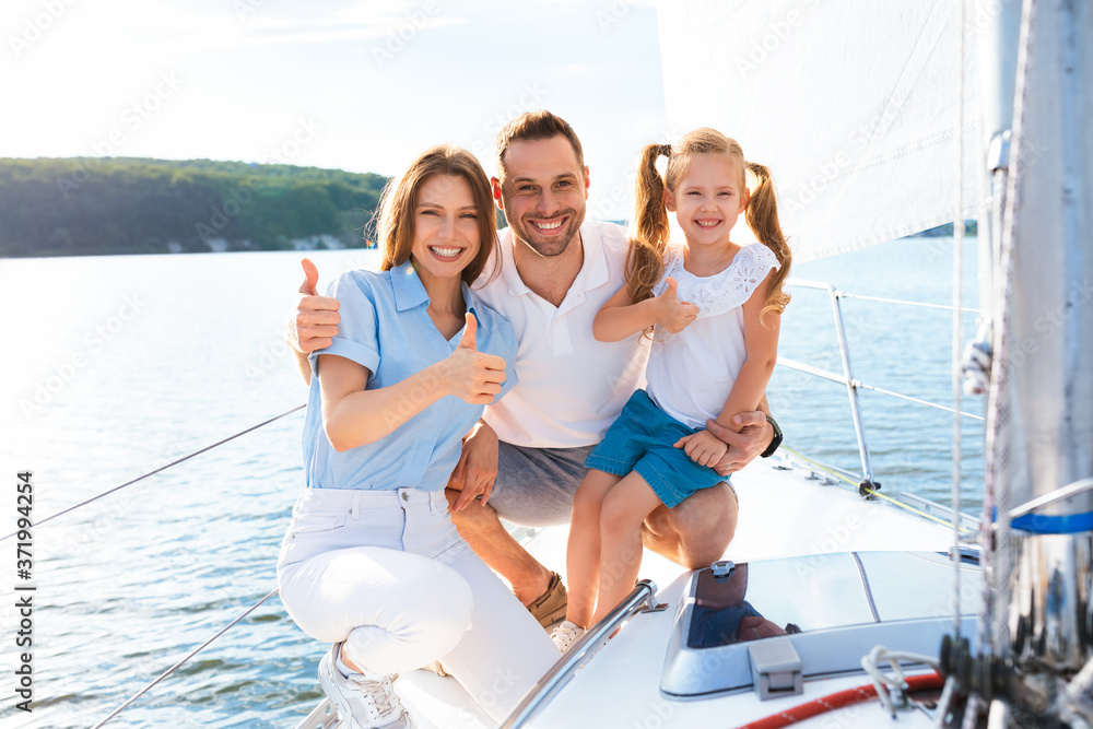 Happy Family On Yacht Gesturing Thumbs-Up Sitting On Sailboat Deck