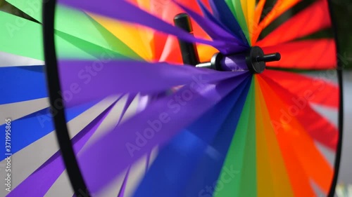 Colorful pinwheel spinning, weather wind vane, garden decoration in USA. Rainbow symbol of childhood, fantasy and imagination rotating. Multi colored spiral toy turning in breeze. Summertime dreaming. photo