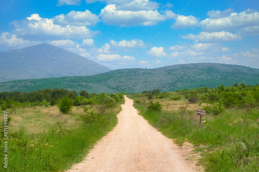 Amazing mountain view of the blooming meadow, rural road and small hut on the mountain Rtanj, Serbia
