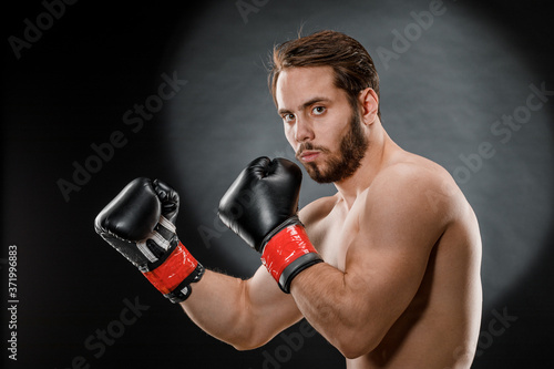 A man in Boxing gloves. A man Boxing on a black background. The concept of a healthy lifestyle © fusssergei