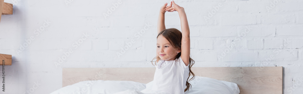 panoramic shot of awakened child stretching while sitting in bed panoramic shot of awakened child stretching while sitting in bed