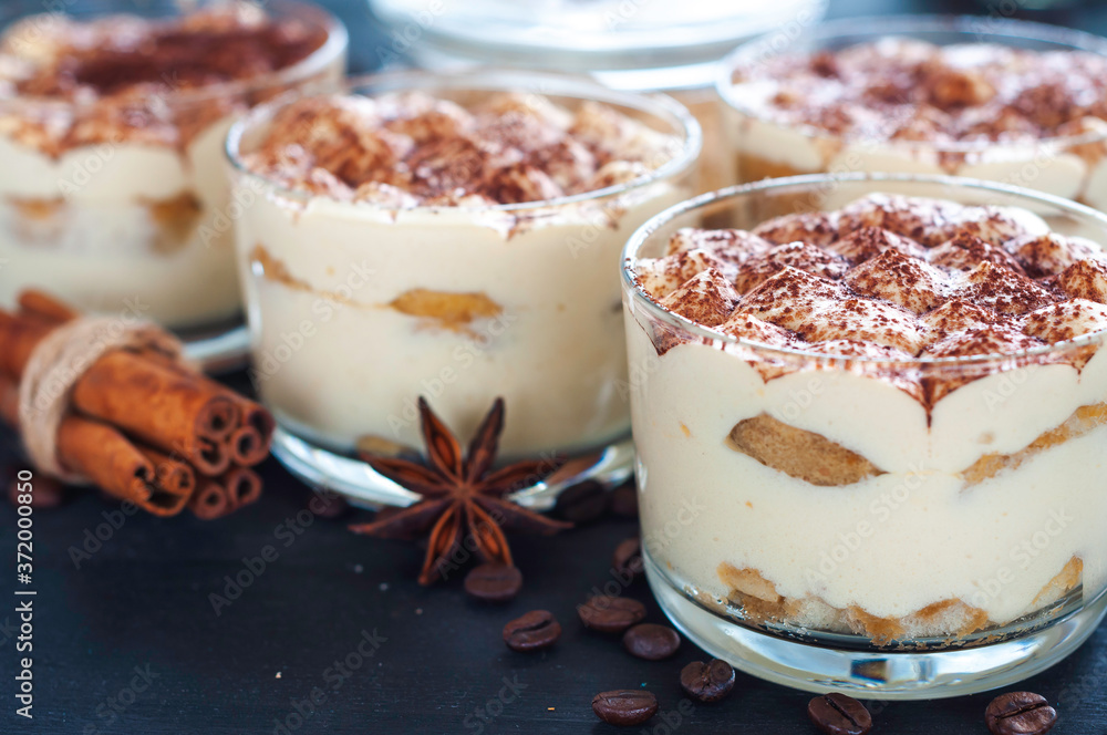 exquisite tiramisu in glasses decorated with cocoa powder on a dark background exquisite tiramisu in glasses decorated with cocoa powder on a dark background
