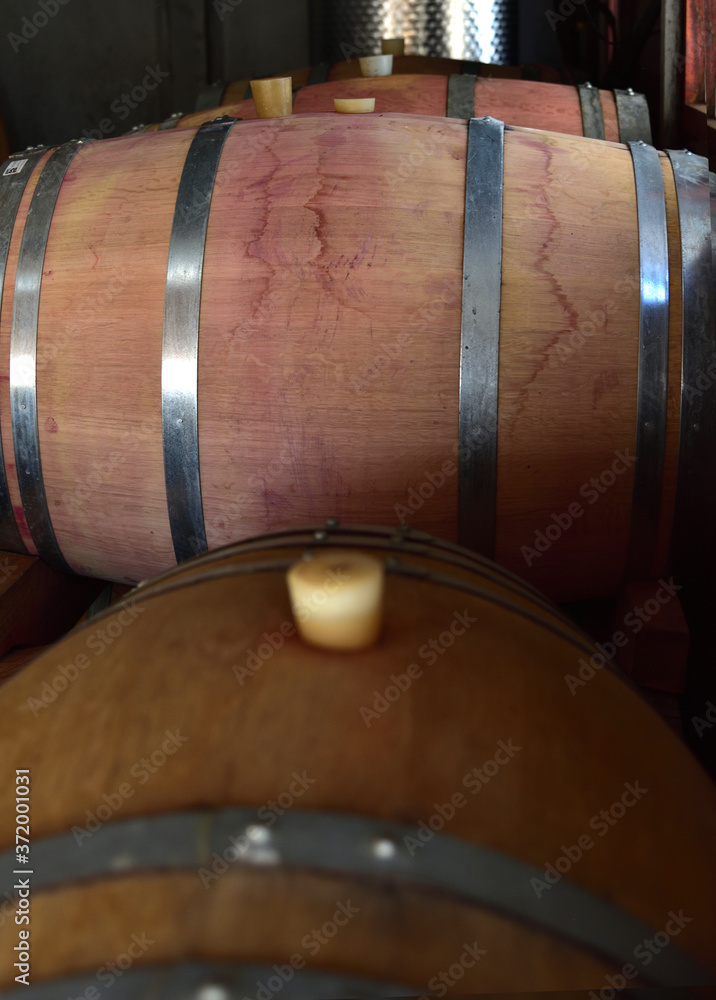 Stacked wine barrels in a garage used for making wine by a garagiste