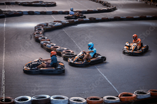 Three guys overtaking each other on an indoor karting track