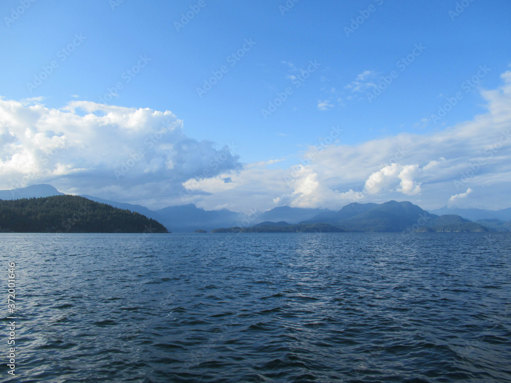 Beautiful landscape with sea, mountains and white clouds on blue sky near Vancouver. Beautiful landscape with sea, mountains and white clouds on blue sky near Vancouver.