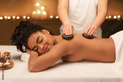 Spa therapist making professional hot stone massage