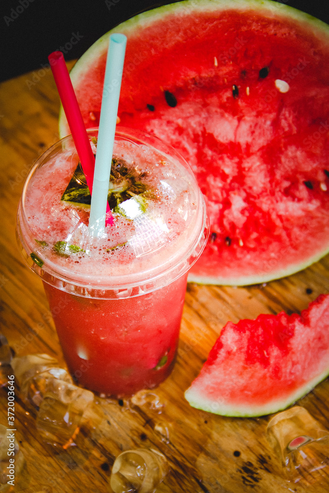 Cold watermelon cocktail with ice cubes on wooden table
Cold watermelon cocktail with ice cubes on wooden table