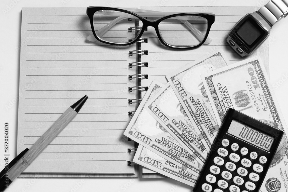 Top view of an open notebook with a pen or pencil, glasses, men's watch, cash, calculator on a white background Top view of an open notebook with a pen or pencil, glasses, men's watch, cash, calculator on a white background