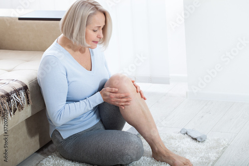 Obraz na plátně Middle-aged woman suffering from pain in leg at home, closeup