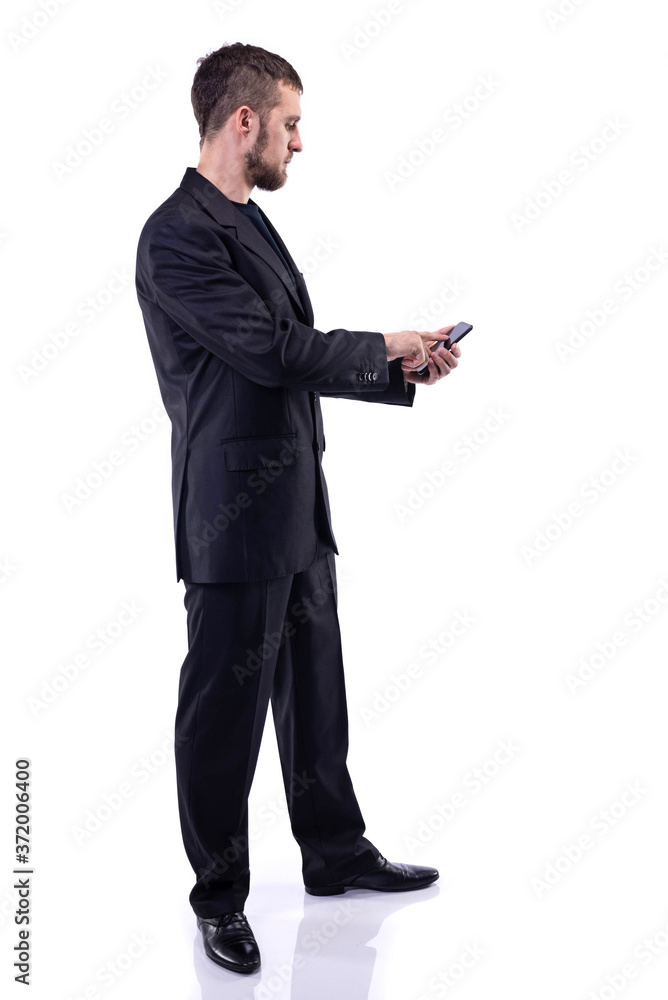 A bearded man in a business suit holds a phone, on a white background.