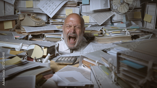 Stressed businessman buried under a lot of paperwork