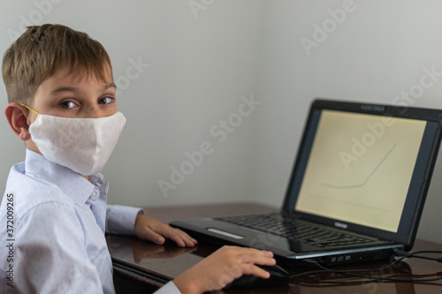 masked boy sitting at the computer