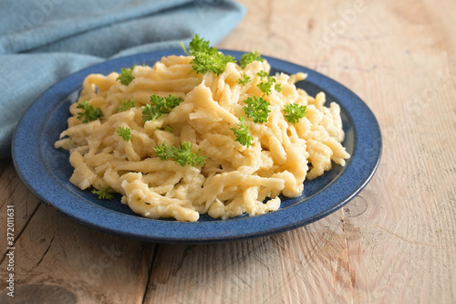 Homemade spaetzle served with parsley garnish on a blue plate and a rustic wooden table, traditional egg pasta in Schwaben, southern Germany and Austria photo