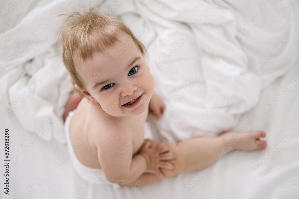 Happy baby one year old smiling in the white bed
