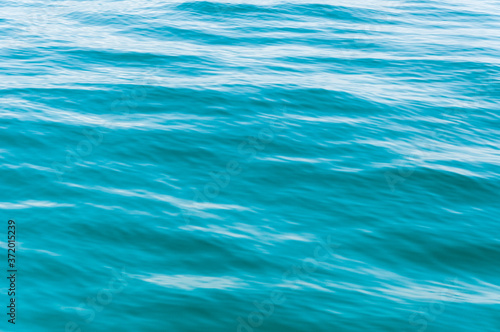 Blurred image of sea water texture in movement. Deep blue and light reflex. Background.