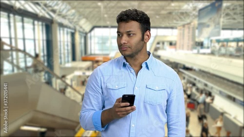 Confident man taking photo with smartphone. Handsome Indian man taking picture with mobile phone. Underground subway background with moving escalator. photo