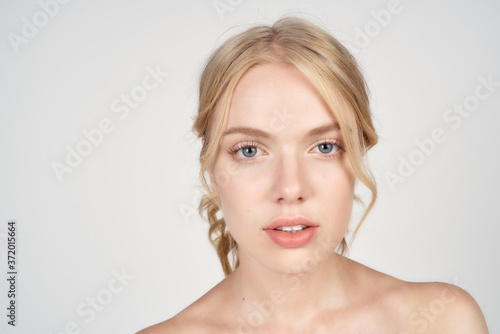 Blonde woman with bare shoulders clean skin lifestyle close-up cropped view light background