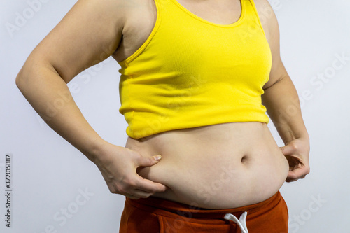 fat female belly with overweight. Woman holds on to fat folds by side close up