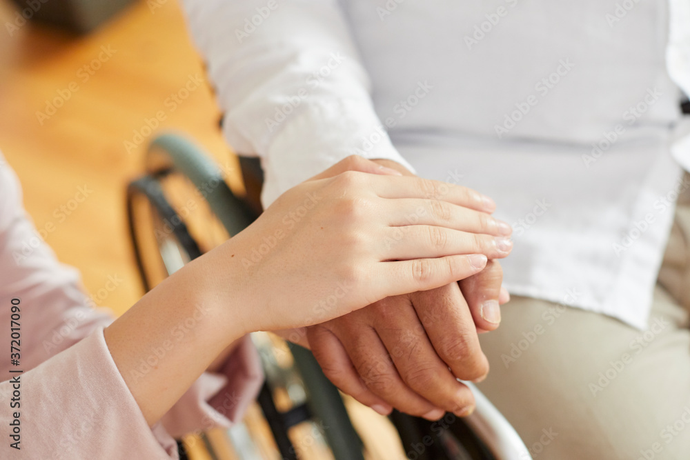 車椅子のシニアの男性を介助する若い女性