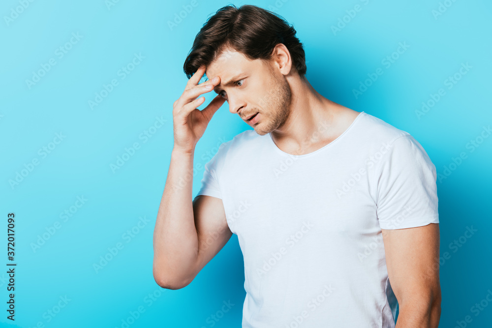 Thoughtful man with hand near head looking away on blue background Thoughtful man with hand near head looking away on blue background