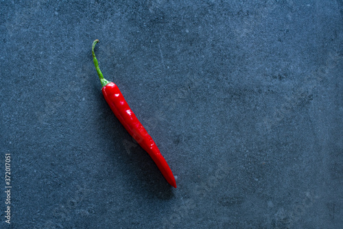 Red hot chilli pepper on blue slate background, flat lay, copy space