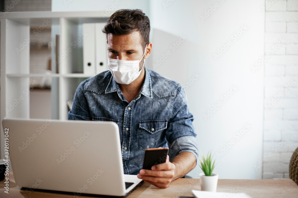 Businessman with medical mask in office. Handsome man using the phone at work.. Businessman with medical mask in office. Handsome man using the phone at work..