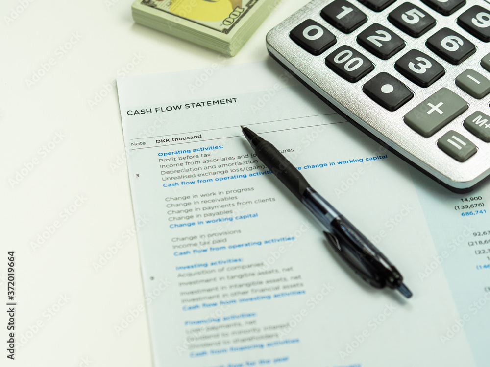 Financial statement concept:Cash flow statement paper sheet with pile of 100 dollars calculator and pen. and pen. Financial statement concept:Cash flow statement paper sheet with pile of 100 dollars calculator and pen. and pen.
