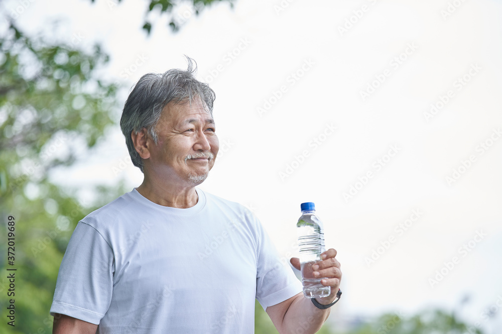 ペットボトルに入った水を持つシニアの男性 ペットボトルに入った水を持つシニアの男性