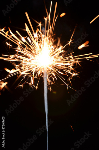 Blurred rays and sparks of sparkler on black background