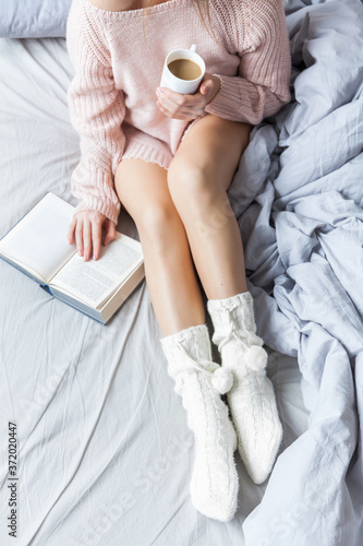 Woman resting keeping legs in warm socks on bed